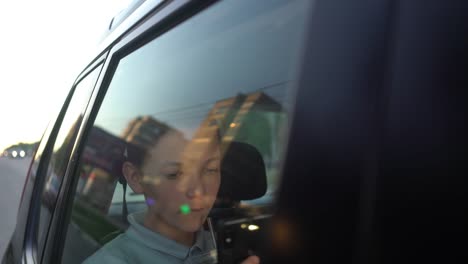 teenager-using-app-on-his-phone-in-the-evening-in-backseat-of-car.