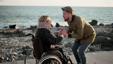 Mann-belebt-seine-geliebte-Frau-im-Rollstuhl-im-Meer-Strand-sitzen