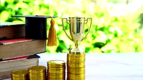 Management-of-Achievement-Champion-mit-Auszeichnungen-Investition-in-Finanzkonzept:-Goldene-Trophäe-auf-den-oberen-Reihen-von-Goldmünzen,-Graduierung-Hut,-Bleistifte-Box,-altes-Lehrbuch.-Erfolg-in-der-Kaufwirtschaft