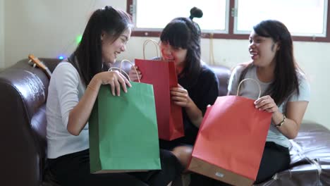 Tres-mujeres-jóvenes-están-disfrutando-de-abrir-bolsas-de-compras