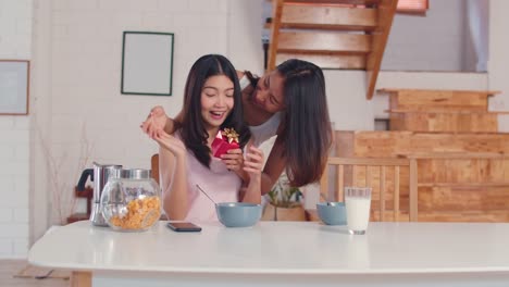 Asian-Lesbian-couple-giving-present-surprise-on-her-birthday-or-Valentines-day-while-having-breakfast-in-kitchen-in-the-morning.