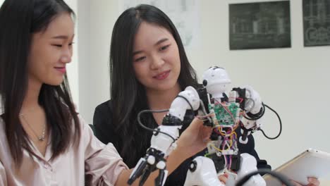 Asiatische-Frau-Ingenieur-Montage-und-Testen-von-Robotik-Antworten-im-Labor.-Architekten-Design-Circuit-Meeting-teilen-Technologieideen-und-kooperierende-Entwicklungsroboter.