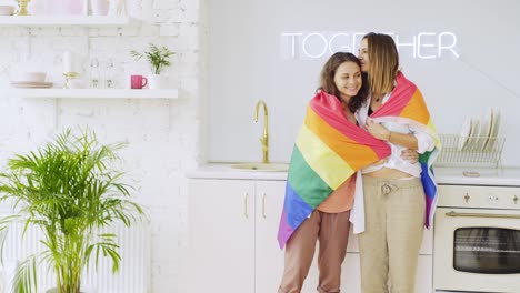 Freundinnen-mit-Regenbogenfahne-in-Wohnung