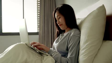 Asian-beautiful-girls-are-using-notebooks-to-play-social-networking-on-the-bed.