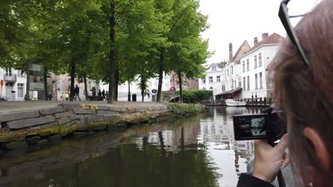 Bruges,-Belgium---May-2019:-View-of-the-water-channel-in-the-city-center.-Tourist-walk-on-the-water-canals-of-the-city.-View-from-a-tourist-boat.