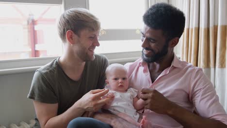 Retrato-de-amar-a-los-hombres-del-mismo-sexo-pareja-abrazando-a-la-hija-del-bebé-en-el-sofá-en-casa-juntos