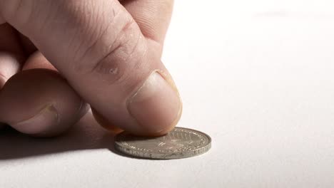 Hand-putting-2-Deutsche-Mark-coin-on-desk,-obverse-side-showing-German-eagle.