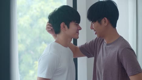 Asian-Gay-couple-standing-and-hugging-near-the-window-at-home.-Young-Asian-LGBTQ+-men-kissing-happy-relax-rest-together-spend-romantic-time-in-living-room-at-modern-house-in-the-morning-concept.