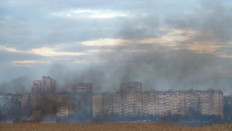 Vista-ansiosa-de-humo-gris-y-negro-que-se-eleva-sobre-los-suburbios-de-los-humedales-de-caña-en-Ucrania-en-primavera-en-cámara-lenta