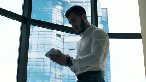 Man-working-on-tablet-PC-near-window