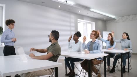 Diverse-Group-of-College-Students-Listening-to-Teacher-and-Raising-Hands