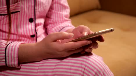 Telefon-ist-in-den-Händen-einer-Frau-in-rosa-Pyjamas.