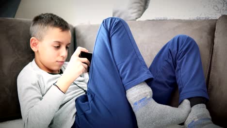 Boy-sits-on-sofa-plays-video-games-with-smartphone