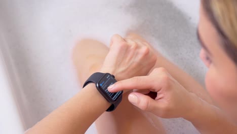 Attraktive-junge-Sportlerin-trägt-und-verwendet-Smartwatch-im-Badezimmer.-Tippen-Sie-auf-den-Bildschirm-des-Smartwatch-Geräts.