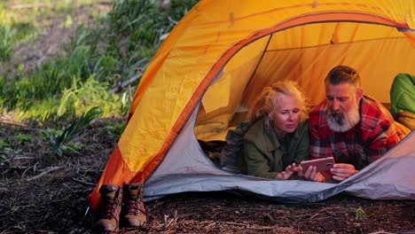 Schließen-Sie-Senior-Paar-mit-Smartphone-in-Zelt-im-Wald