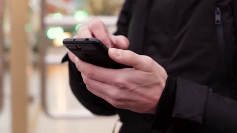 Close-up-of-young-man-hands-using-smartphone-outdoors