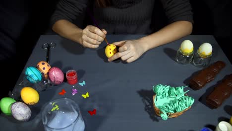 Female-hands-painting-the-egg-decoration-for-easter-over-a-gray-background.