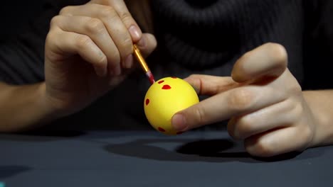 Female-hands-painting-the-egg-decoration-for-easter-over-a-gray-background.