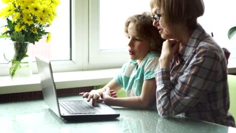 Die-Großmutter-und-der-Enkel-mit-Interesse-schauen-auf-den-Laptop-Bildschirm.