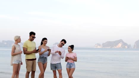 People-Walking-On-Beach-Talking-Using-Cell-Smart-Phones,-Young-Tourists-Group-Networking-Online