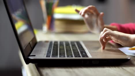 Little-girl's-hands-on-computer-keyboard-indoors