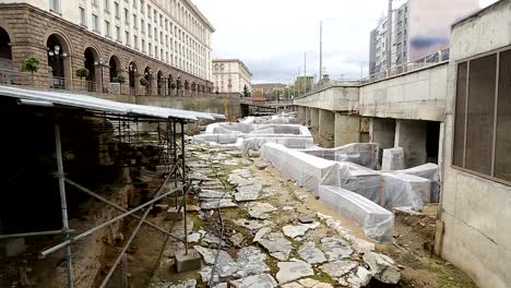 Ancient-ruins-excavated-in-middle-of-street-surrounded-by-monumental-buildings