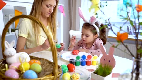 Happy-Easter!-Mother-and-her-little-daughter-wearing-funny-rabbit-ears-coloring-easter-eggs