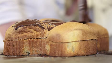 pastry-chef--hands-glazed-Easter-sweet-bread-cakes-with-chocolate,-closeup-on-the-worktop-in-confectionery