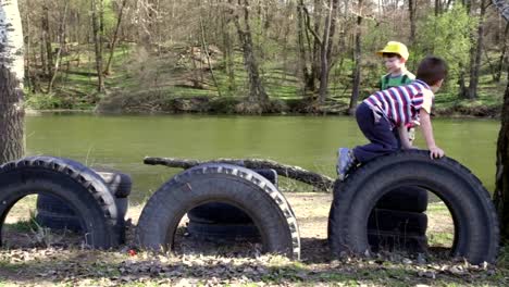 Two-kids-playing-together,-jumping-and-climbing-on-tires