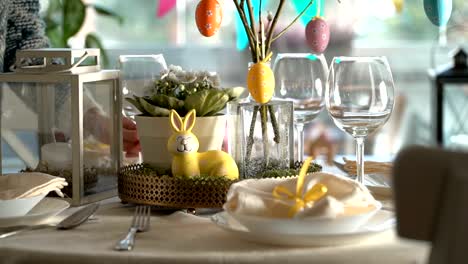 Young-woman-setting-easter-festive-table-with-bunny-and-eggs-decoration