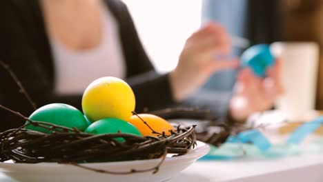 Semana-Santa,-vacaciones,-concepto-de-tradición-y-gente---cerca-de-las-manos-de-mujer-para-colorear-huevos-de-Pascua-con-colores-y-pincel.-Concepto-de-Pascua-Feliz