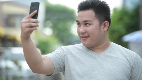 Young-handsome-overweight-Asian-man-in-the-streets-outdoors