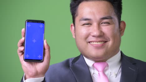 Young-handsome-overweight-Asian-businessman-against-green-background