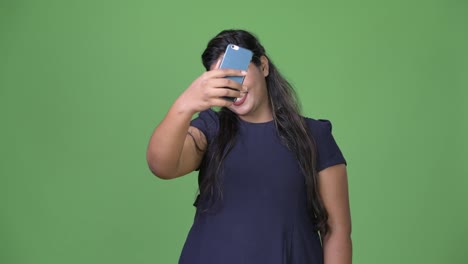 Young-overweight-beautiful-Indian-businesswoman-against-green-background