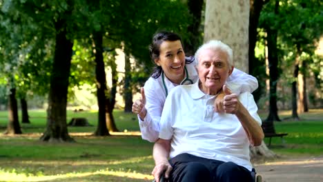 Médico,-enfermera,-cuidado-personas-mayores,-niña-(mujer)-y-abuelo-sentado-en-una-silla-de-ruedas,-caminar-en-el-parque.