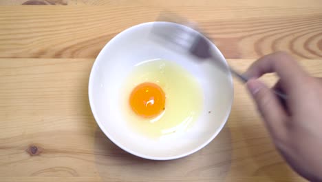 Close-up-of-hands-beat-egg-in-a-white-bowl-to-prepare-omelet-in-morning-for-breakfast.