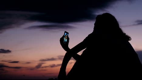 Silueta-de-una-niña-utiliza-un-smartphone-para-vivir-en-las-redes-sociales-al-atardecer