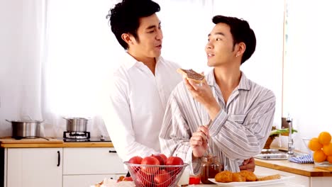 Happy-gay-couple-sweet-at-home-kitchen.-Man-cooking-breakfast-for-him-boyfriend-with-attractive-smiling.-People-with-gay,-homosexual,-relationship-concept.