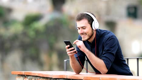 Glücklicher-Mann-anhören-von-Musik-vom-Handy-auf-einem-Balkon