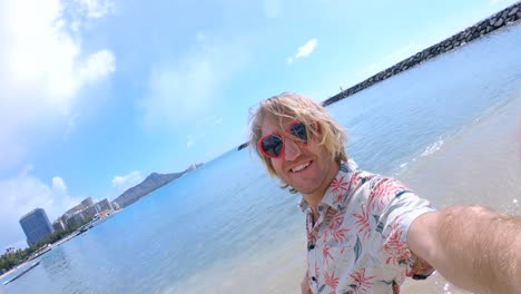 Junger-Mann-mit-Herz-Form-rot-Sonnenbrille-Selfie-Aufnahme-am-Strand-von-Waikiki-in-Honolulu-Hawaii