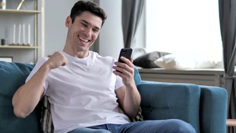 Joven-emocionado-por-el-éxito,-ganando-en-línea-en-Smartphone