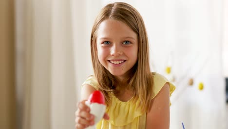 happy-girl-showing-colored-easter-egg-at-home