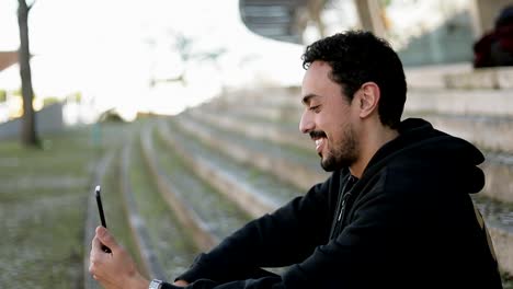 Side-view-of-Arabic-man-having-video-chat-outside,-waving-hand