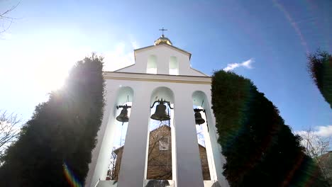 Kirchliche-Glocken-an-einem-Sonnentag-bei-starkem-Wind-Der-Wind-schüttelt-die-Bäume-in-der-Nähe-des-Glockenturms-und-Sonechka-leuchtet-in-der-Zelle-in-der-Nähe-der-Kirchenglocken