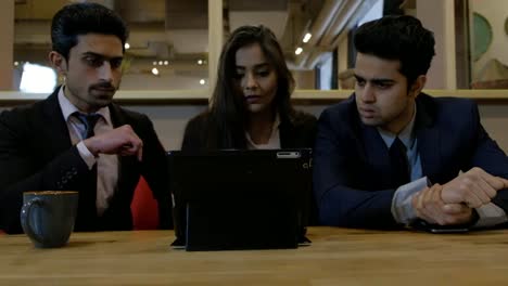 Handheld-shot-of-young-Indian-coworkers-colleagues-huddled-together-as-they-work-on-computer-and-work-out-a-solution-to-their-management-issues