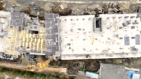 Construction-of-a-high-rise-building,-a-view-from-the-top-with-a-drone.-Workers-build-a-house.-Panorama-from-the-top-of-the-construction-site