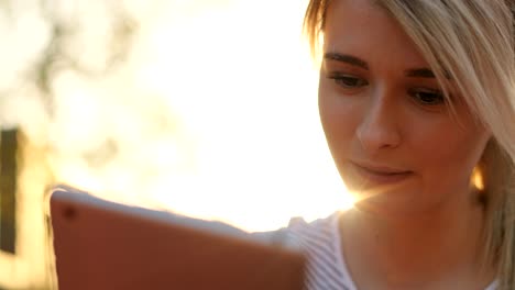 Close-up-portrait-of-young-female-student-using-tablet-computer-in-the-park.-Girl-doing-online-shopping-on-tablet-pc