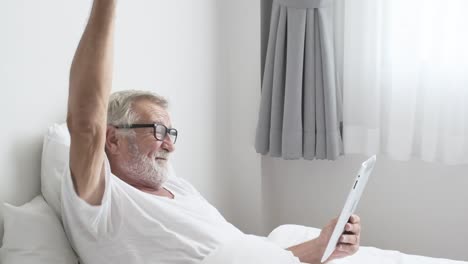 Grandfather-or-senior-man-using-tablet-technology-and-cheer-up-on-bed