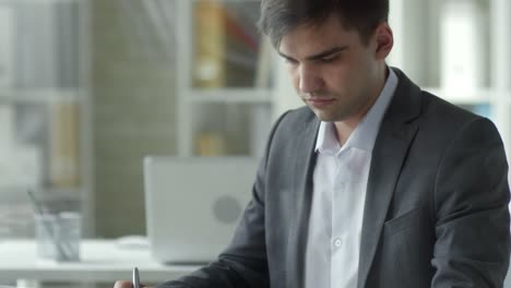 Kaukasischer-Geschäftsmann-nutzt-Tablet-und-Notizen-an-Office-Desk