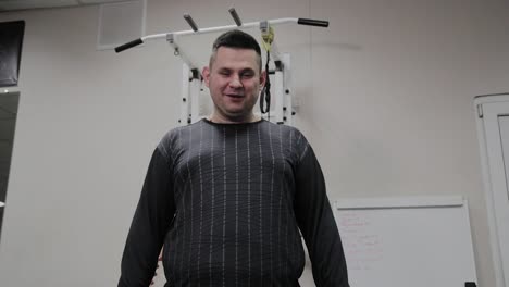 Cheerful-fat-man-performs-a-wrong-exercise-in-the-gym.-For-the-first-time-in-a-fitness-club